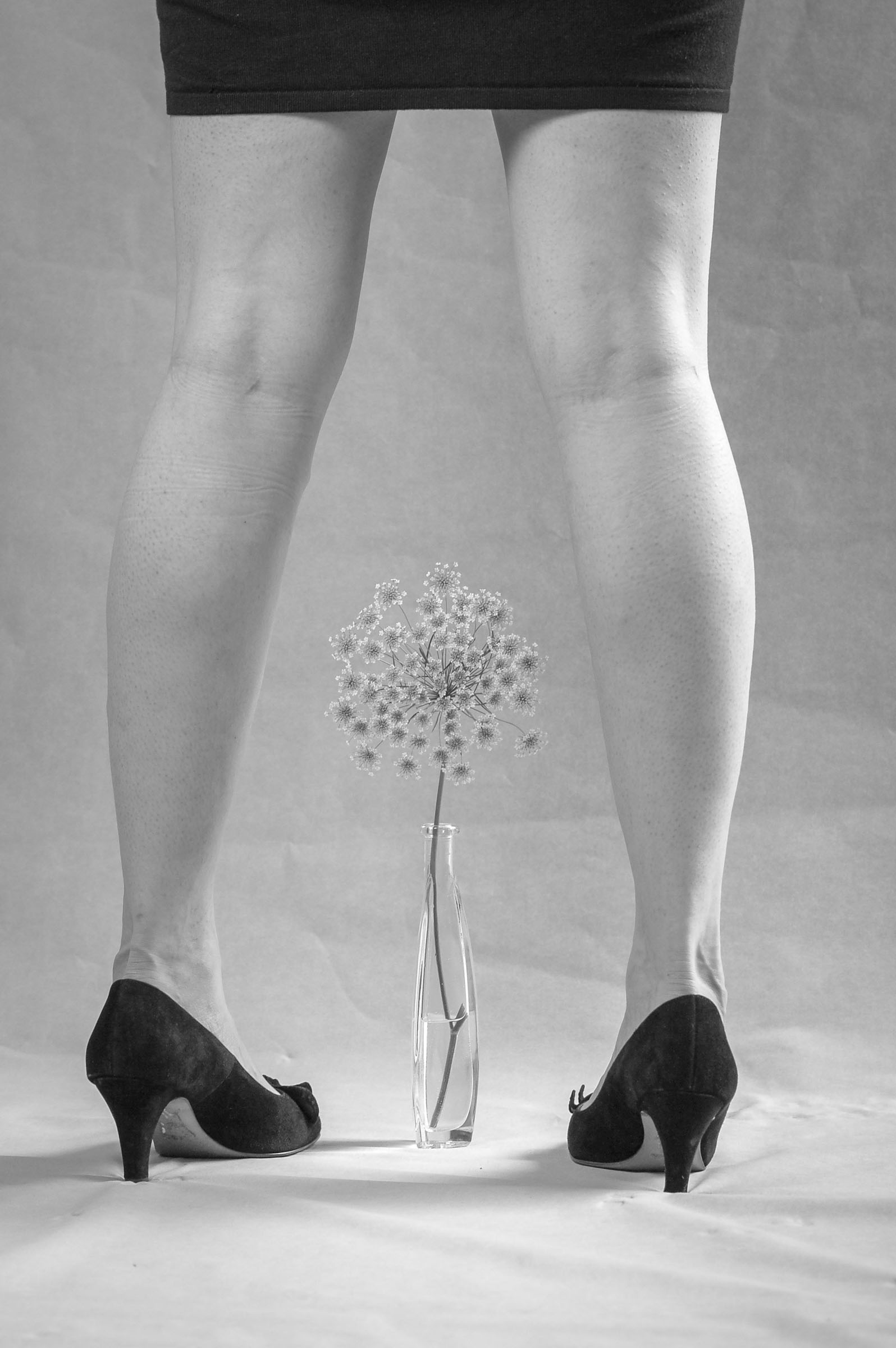 Beine einer Frau von hinten mit Doldenblume